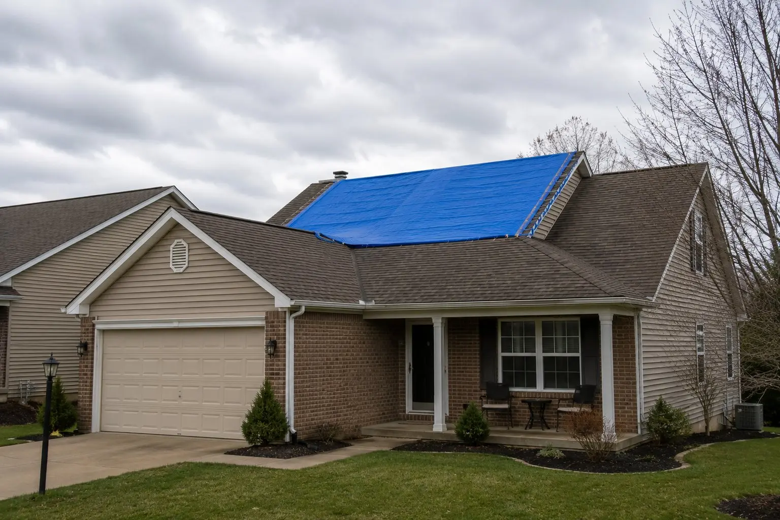 Blue emergency tarp covering wind-damaged section of a brick ranch home in Licking County Ohio after a severe storm