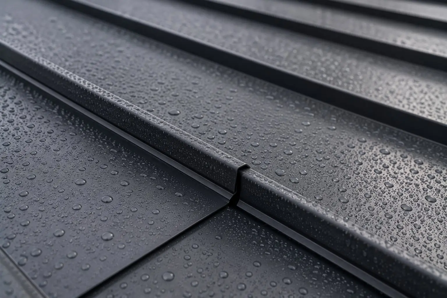 Close-up of water beading on dark charcoal standing seam metal roofing panels showing the waterproofing performance of a properly installed metal roof