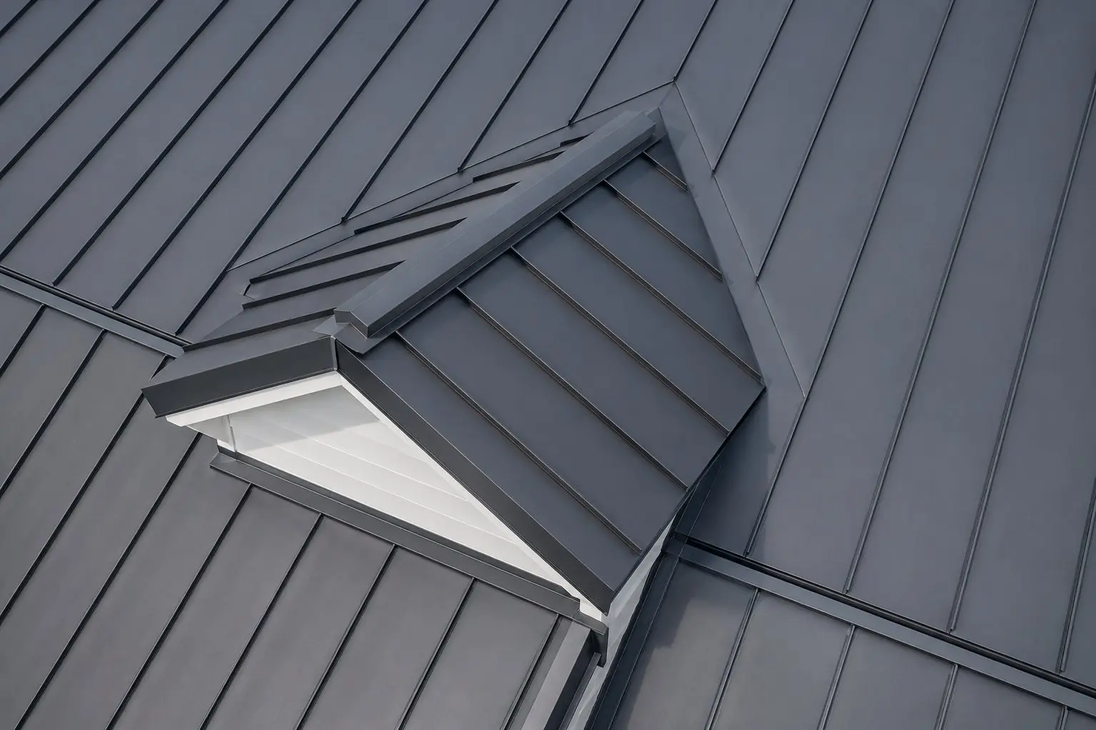 Close-up architectural detail of charcoal standing seam metal roof panels with precision lock seams and dormer flashing on an Ohio home